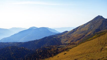 Fototapeta premium A beautiful panorama of mountains, aerial perspective, distant peaks in a blue haze, freedom and beauty of nature. Autumn view of the Caucasus mountains in Russia