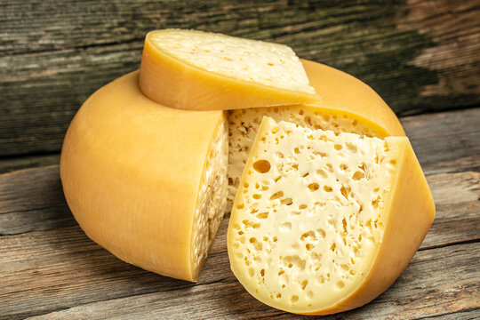 close up french hard cheese with holes emmentaler on a wooden background. farmer market. place for text