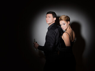 An attractive couple in black. Stylish and elegant young man and woman in the spotlight. Beautiful...