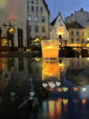   evening city light  and  glass  cup with  candle light on table on medieval street evening blurred bokeh light  under rain drops on window  in Tallinn old town Autumn  holiday in Estonia