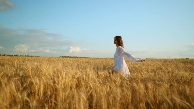 brunette girl is running in beautiful rye field with golden ears, admiring and inspiring by beauty of nature