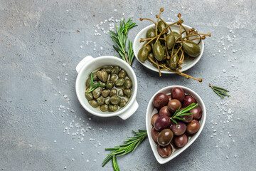 Marinated capers fresh basil leaves in a small bowl, on gray background. Long banner format. top view