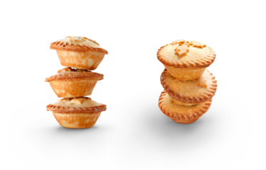 A collection of Christmas mince pies staked, piled up isolated against a flat background.
