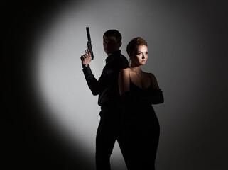 Super agents, a gorgeous blonde in a black evening outfit and a man with a gun behind her back. A...
