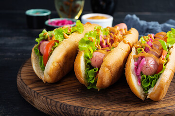 Hot dog with lettuce, tomatoes and pickled onions. Grilled bun with sausage