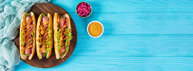 Hot dog with lettuce, tomatoes and pickled onions. Grilled bun with sausage