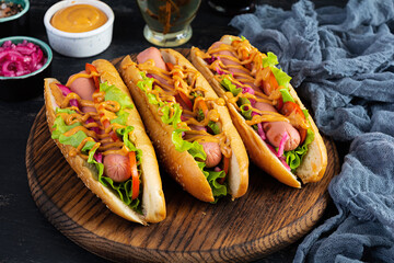 Hot dog with lettuce, tomatoes and pickled onions. Grilled bun with sausage