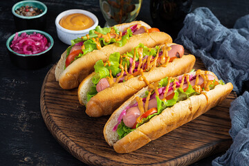 Hot dog with lettuce, tomatoes and pickled onions. Grilled bun with sausage