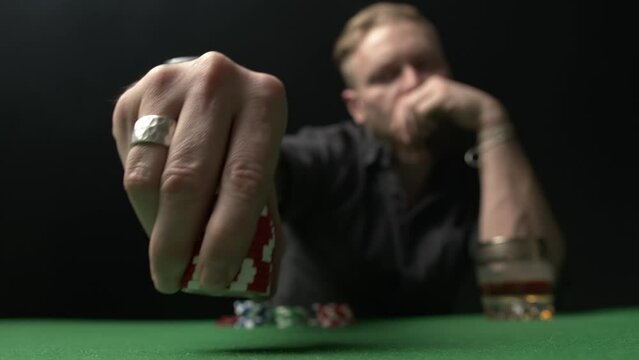 A poker player makes a bet. Takes a stack of red chips and confidently puts them on the table close-up