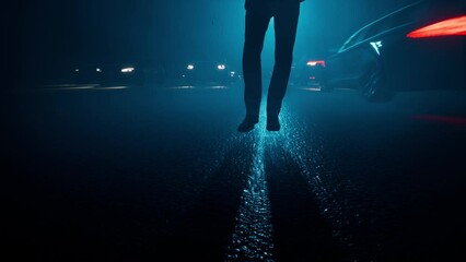 A lone man walks in the middle of the road in the rain in the evening between passing cars. The concept of loneliness, bad mood, disappointment, separation.