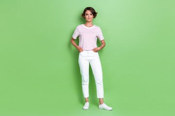 Fototapeta na wymiar Full body photo of stunning young woman hold hands pockets promoter model dressed trendy striped clothes isolated on green color background