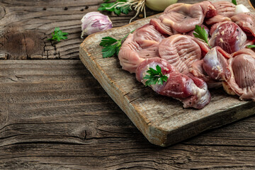 Raw uncooked chicken gizzards, stomach on a wooden background. Traditional Korean spicy chicken meat. Long banner format. top view