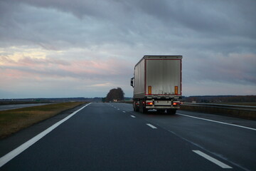 Fototapeta na wymiar White heavy truck on countryside highway road on dramatic clouds background. Uhfnsportation logistics in Europe
