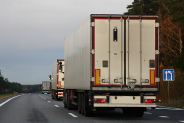 White heavy trucks convoy on countryside highway road. Goods delivery in Europe