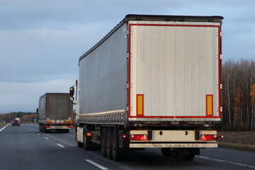 White heavy trucks convoy on countryside highway road.