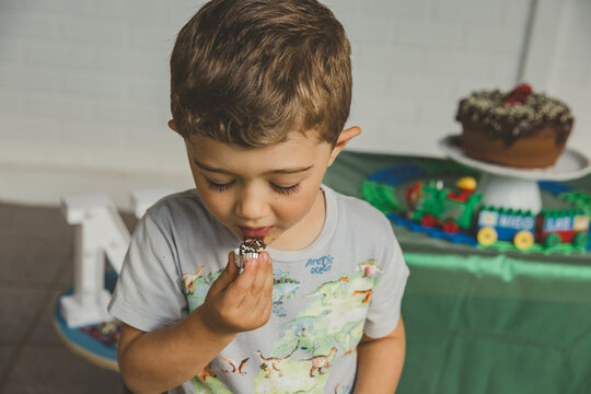 menino comendo bolo de chocolate e brigadeiro em anivers&aacute;rio