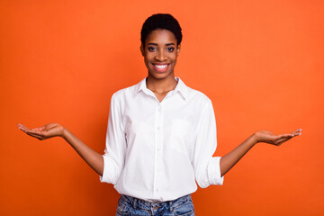 Photo of positive emotion lesbian female compare products alternative offer wear stylish man style shirt isolated on orange color background