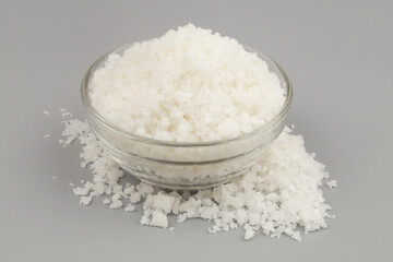 Bowl with coarse sea salt on gray background.	