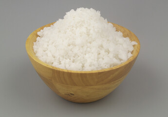 Coarse sea salt in wooden bowl on gray background.	