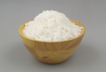 Coarse salt in wooden bowl on gray background