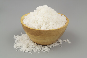 Sea salt in wooden bowl on gray background.	