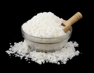 Coarse salt in glass bowl with wooden scoop isolated on black background.	