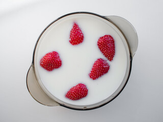 Plate with strawberry in form of smile in milk on white background