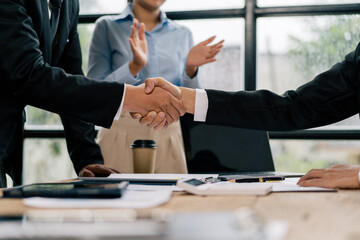 Close up of female and male shaking hands, businessman and businesswoman handshaking at office table with charts graphs after successful negotiations, partners concluding contract
