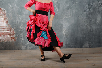 Young adult spanish woman dancing flamenco on gray vintage studio background legs close up