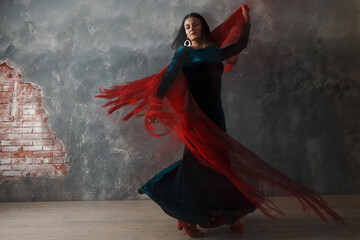 Young adult spanish woman dancing flamenco on gray vintage studio background