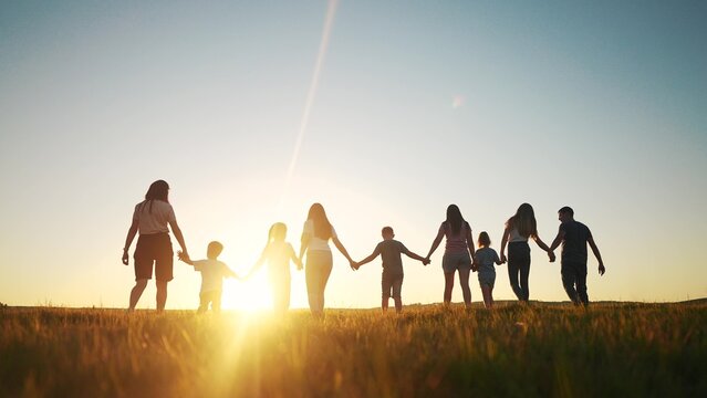 community large family in the park. a large group of people holding hands walking silhouette on nature sunset in the park. big family kid dream concept. people in lifestyle the park. large family