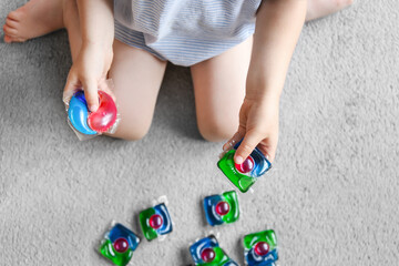 child playing with laundry capsules, washing gel capsules. Keep household chemicals away from...