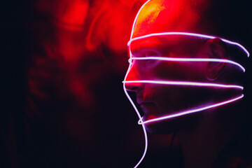 Portrait of man with neon glow tube lines on his face in dark. Concept cyberpunk and virtual reality