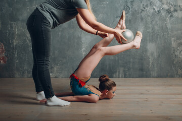 Young girl professional gymnast with coach woman dance rhythmic gymnastics at studio.