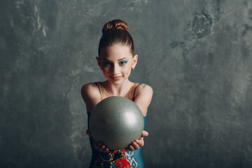 Young girl professional gymnast woman portrait rhythmic gymnastics with ball at studio.