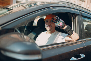 Young disabled man driver with artificial prosthetic hand driving vehicle car