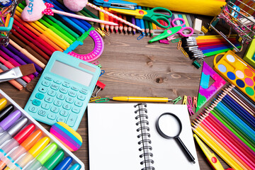 School supplies. Set of colorful school accessories isolated on the brown wooden background. Top...