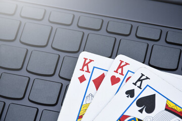Paper cards on blank laptop keyboard, soft and selective focus, concept for playing  cards online with other people at home and recreational activity.