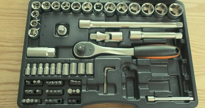 Man's hand opens a set of tools, takes a ratchet socket wrench. Top view, close-up.
