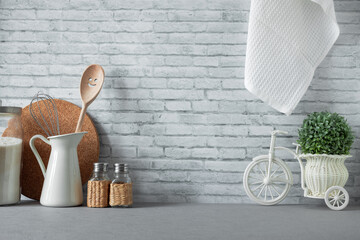 Kitchenware and utensils on a grey countertop. Kitchen with a brick wall background and copy space....
