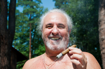 positive senior man smoking cuban cigar enjoying summer vacation and suntan on retirement