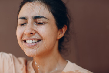 Stressed woman suffering of heatstroke and refreshing pouring with cold water outside. Weather abnormal heat concept