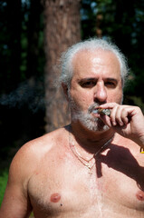 aged man smoking cuban cigar enjoying summer vacation and suntan on retirement
