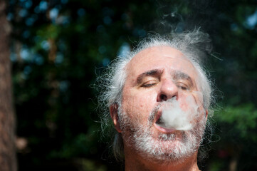 senior man enjoying smoking at summer vacation and suntan. smoke and copy space