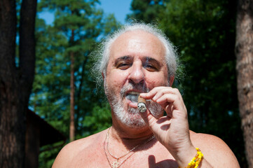 cheerful senior man smoking cuban cigar enjoying summer vacation and suntan on retirement