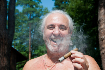 glad senior man smoking cuban cigar enjoying summer vacation and suntan on retirement
