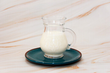 fermented milk drink ayran in a transparent decorative mug on a blue ceramic plate