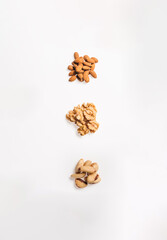 Three piles of almonds, walnuts and brazil nuts, lined up vertically, isolated on white