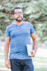 Fototapeta premium handsome businessman walking with his laptop through park