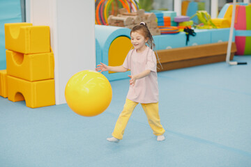 Kids doing exercises with big ball in gym at kindergarten or elementary school. Children sport and fitness concept